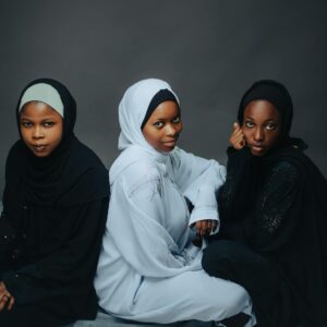 Three women in stylish hijabs seated gracefully, showcasing cultural fashion.