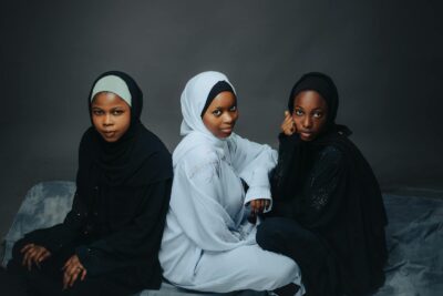 Three women in stylish hijabs seated gracefully, showcasing cultural fashion.